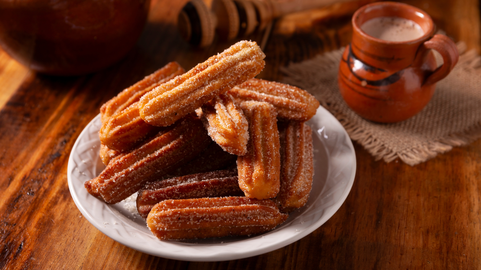 A group of churros on a white plate, dusted in cinnamon sugar.